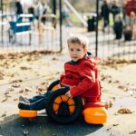 Dwoje dzieci bawiących się jeździkiem Firefly Scooot nad wodą