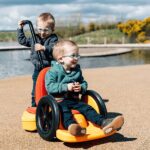 Dziewczynka sięgająca po zabawki, siedząc na jeździku Firefly Scooot